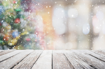 Empty wood table top on blur with bokeh Christmas tree and new's year decoration on window background with snowfall - can be used for display or montage your products.