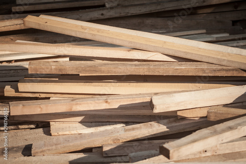 Wooden planks, rods and poles, stockes in piles and stacks, waiting to be used as lumber by a carpenter on a construction site