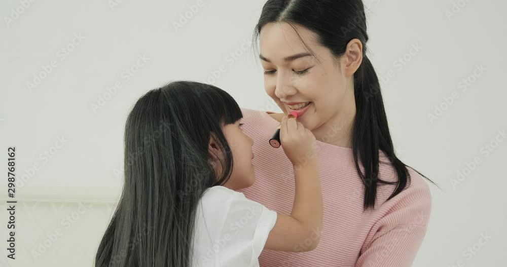 Mother and her daughter playing together at home. Girl make up her mother face with funny emotion. Mother and her daughter playing together at home. Girl make up her mother face with funny emotion.