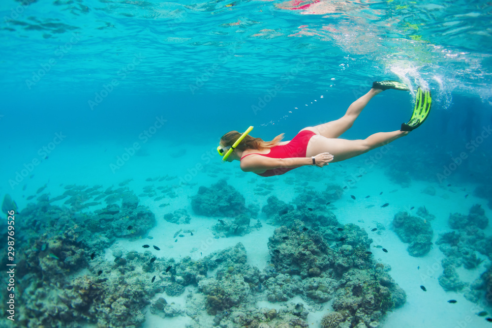 Young happy girl in snorkeling mask jump and dive underwater to see tropical fishes in coral reef sea pool. Travel activity, water sports, outdoor adventure, on family summer beach holiday with kids