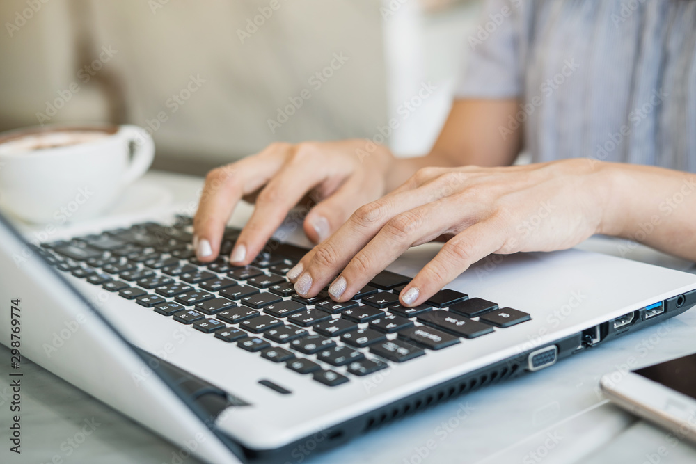 Young woman using smart phone and laptop with cup of coffee in cafe Young woman using smart phone and laptop with cup of coffee in cafe