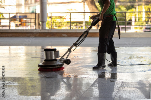 The worker cleaning floor exterior walkway using polishing machine and chemical or acid