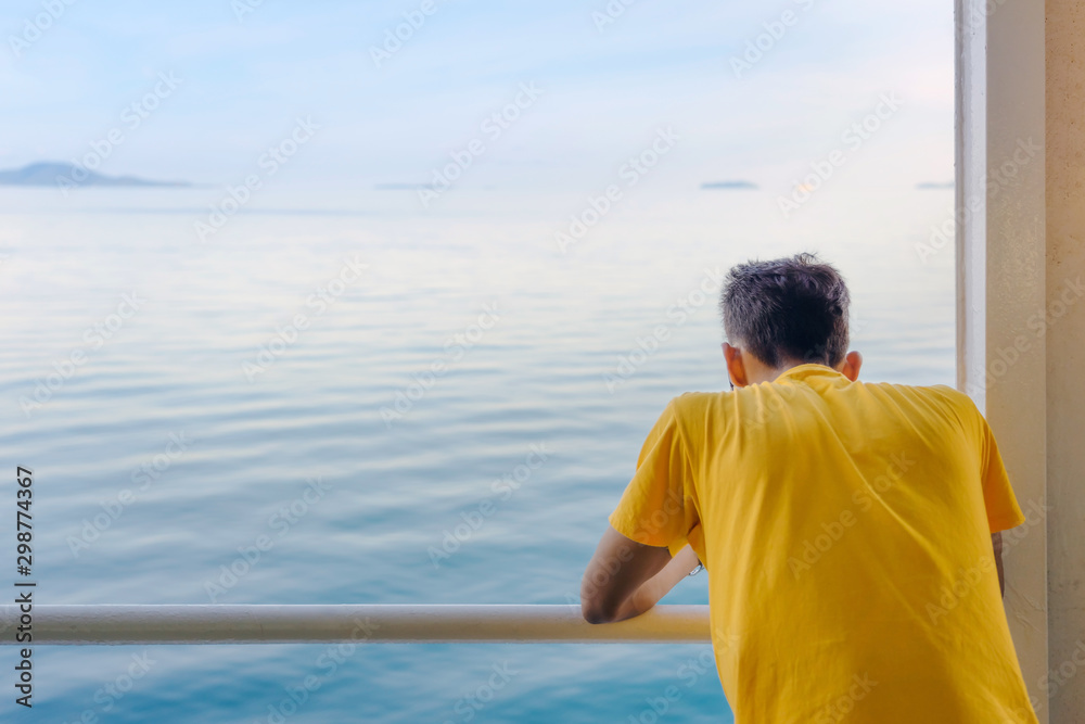 Asian man stands on baluster of ferry for relaxing and look at the ocean and island. Asian man stands on baluster of ferry for relaxing and look at the ocean and island.