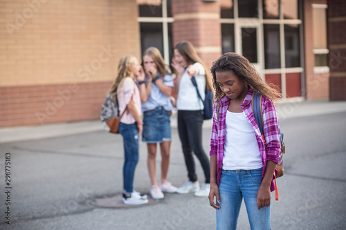 One student being bullied and talked behind back while other students gossiping. Social and school bully concept.