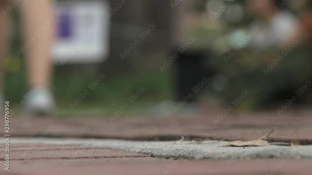 Low angle of brick path as college students walk past, extreme close up Low angle of brick path as college students walk past, extreme close up