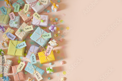 Gift boxes and pastel color confetti. Pink background. Label with the words sale.