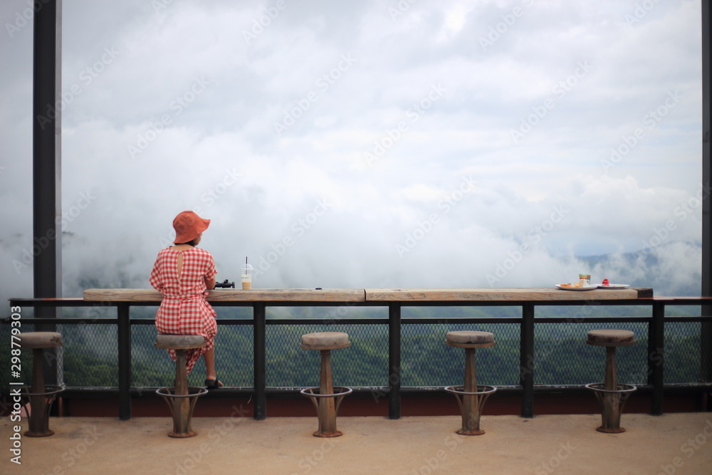 A woman sitting and watching the scenery from the top of the hill
