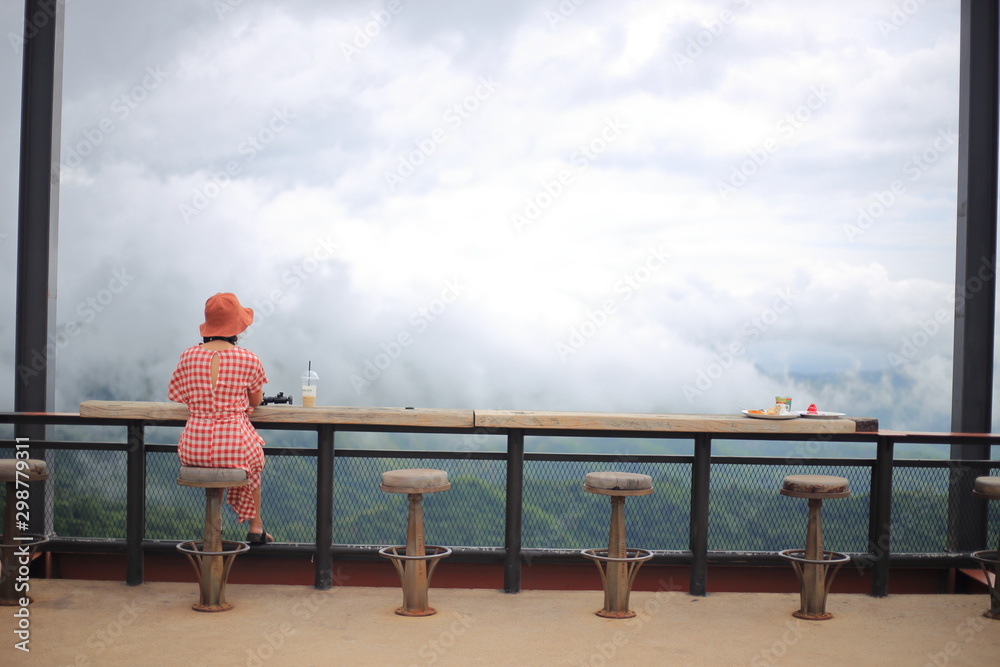 A woman sitting and watching the scenery from the top of the hill A woman sitting and watching the scenery from the top of the hill