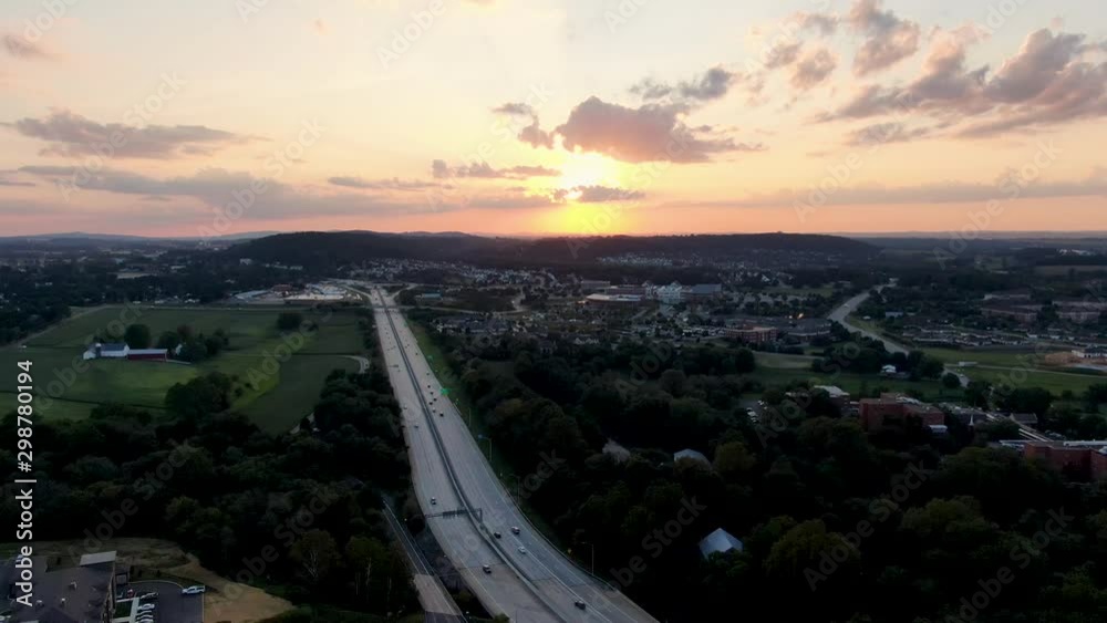 Descending aerial of beautiful summer sunset above busy highway in USA, suburban sprawl Descending aerial of beautiful summer sunset above busy highway in USA, suburban sprawl