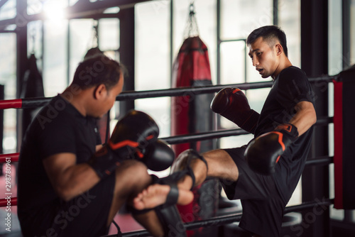 Asian kickboxing player and him trainer in boxing gym photo