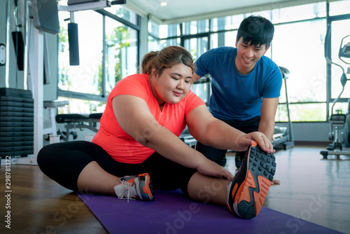 Asian woman stretching with trainner in fitness center