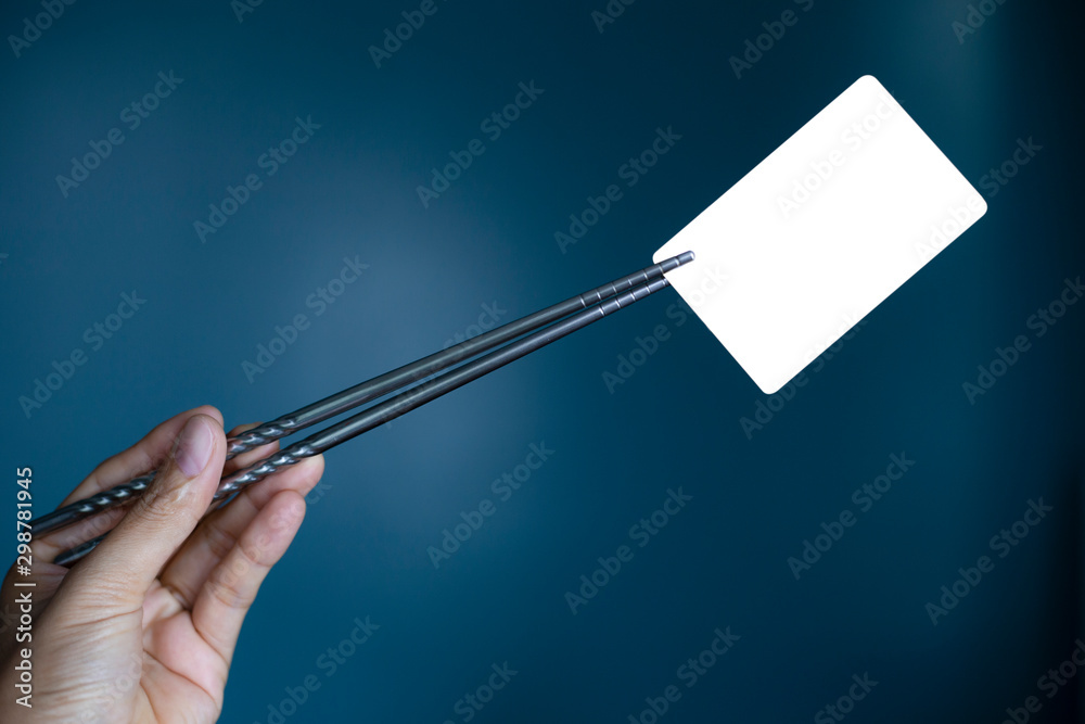 Hold holding chopsticks on a blank piece of paper. Close up White business card.