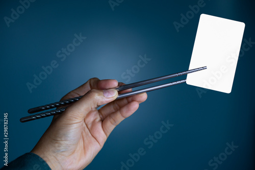 Hold holding chopsticks on a blank piece of paper. Close up White business card.