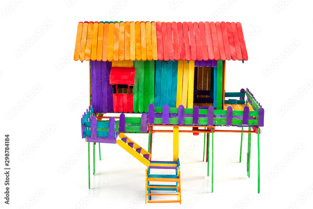 The house is made of toys from colorful popsicle sticks isolated on a white  background. Stock Photo