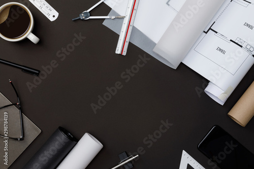 Creative flat lay of architects black table with roll blueprints, architectural project plan, engineering tools, office supplies and a cup of hot coffee, Workspace for new designer concept