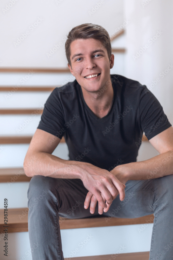 cheerful young man sitting on the steps in his house cheerful young man sitting on the steps in his house