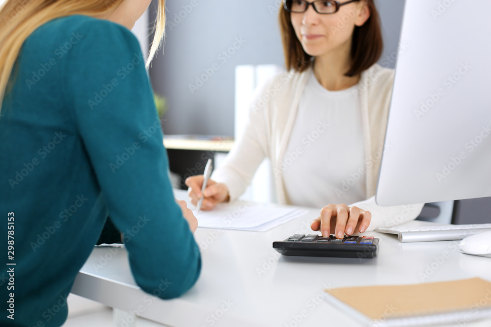 Accountant checking financial statement or counting by calculator income for tax form, hands close-up. Business woman sitting and working with colleague at the desk in office. Audit concept Accountant checking financial statement or counting by calculator income for tax form, hands close-up. Business woman sitting and working with colleague at the desk in office. Audit concept