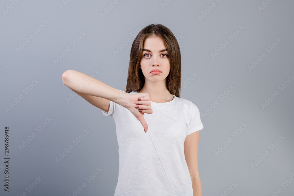 unhappy sad young woman showing thumbs down isolated over grey unhappy sad young woman showing thumbs down isolated over grey