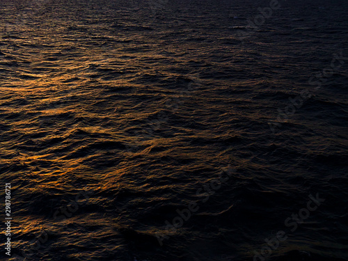 Sunlight on dark sea water during sunset time, while sailing.