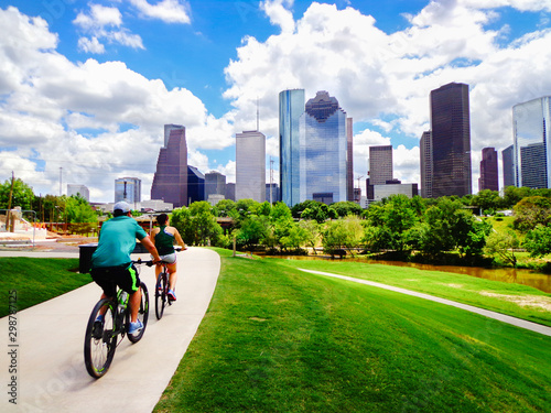 Riding Bikes on Paved Trail in Houston Park (view of river and skyline of downtown Houston) - Houston, Texas, USA  photo