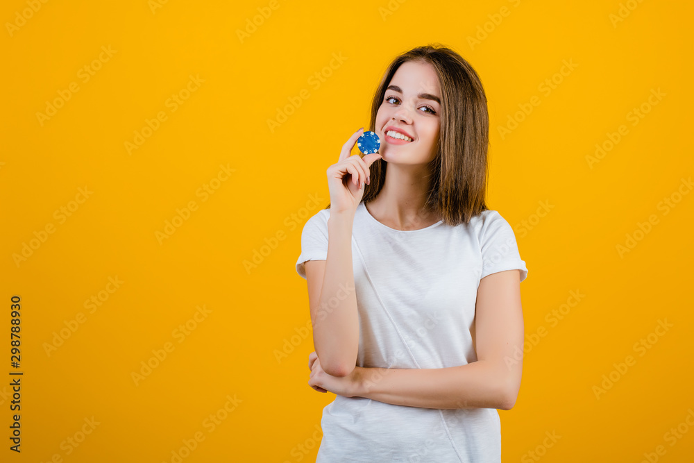 beautiful brunette woman with blue poker chip from online casino isolated over yellow beautiful brunette woman with blue poker chip from online casino isolated over yellow