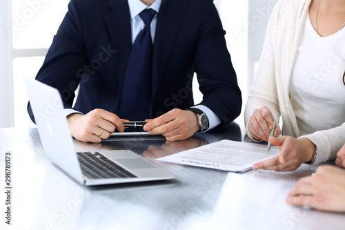 Business people discussing contract working together at meeting at the glass desk in modern office. Unknown businessman and woman with colleagues or lawyers at negotiation. Teamwork and partnership