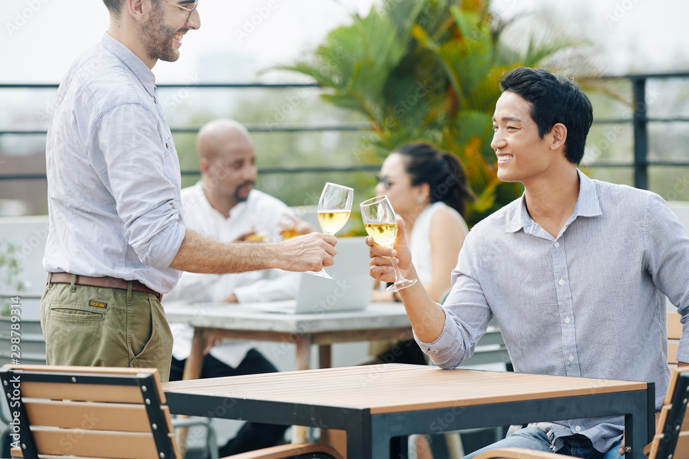 Business people smiling and clinking with champagne glasses at outdoor party