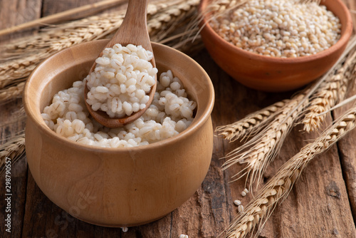 Cooked peeled barley grains in wooden bowl