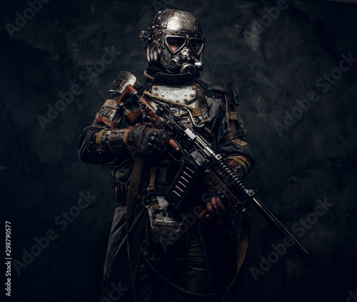 Fototapeta Naklejka Na Ścianę i Meble -  Concept of post - apocalypse futuristic warrior with weapon in hands at dark photo studio.