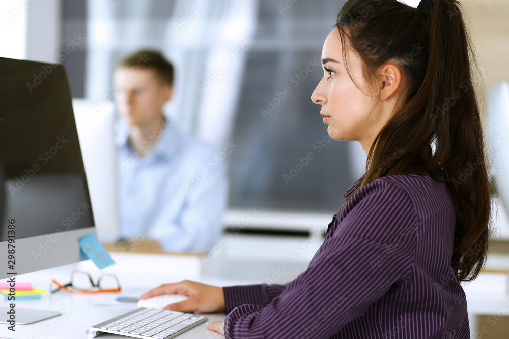 Business woman using computer at workplace in modern office. Brunette secretary or female lawyer smiling and looks happy. Working for pleasure and success Business woman using computer at workplace in modern office. Brunette secretary or female lawyer smiling and looks happy. Working for pleasure and success