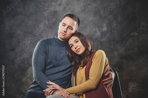 Handsome man is hugging his attractive happy woman at photo studio.