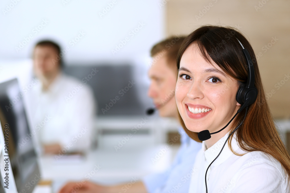 Call center. Group of diverse operators at work. Focus on beautiful asian woman in headset at customer service office. Business concept Call center. Group of diverse operators at work. Focus on beautiful asian woman in headset at customer service office. Business concept