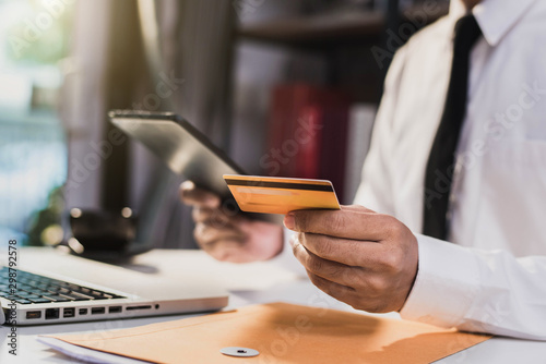 Male businessman use credit cards to conduct financial transactions through phones, tablet, and laptop.