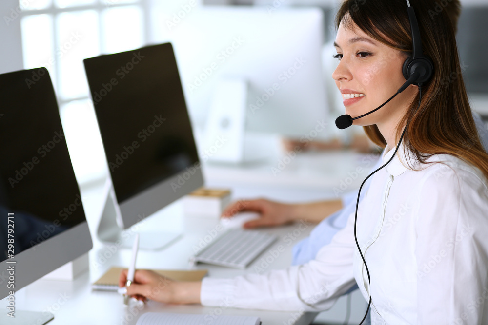 Call center. Group of diverse operators at work. Focus on beautiful asian woman in headset at customer service office. Business concept Call center. Group of diverse operators at work. Focus on beautiful asian woman in headset at customer service office. Business concept
