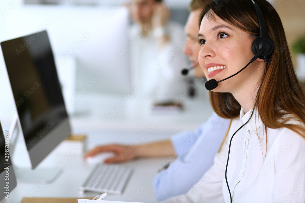 Call center. Group of diverse operators at work. Focus on beautiful asian woman in headset at customer service office. Business concept Call center. Group of diverse operators at work. Focus on beautiful asian woman in headset at customer service office. Business concept