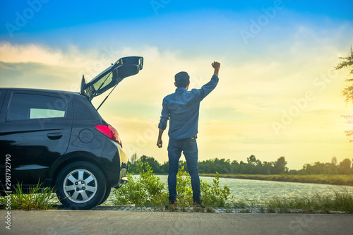 Man Standing at Car parked on road,Boy Holding hand success at Car on street Sky sunlight background