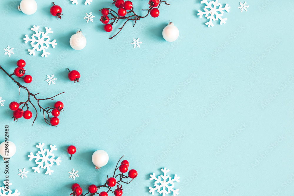 Fototapeta Kompozycja świąteczna lub zimowa. Płatki śniegu i czerwone jagody na niebieskim tle. Boże Narodzenie, zima, koncepcja nowego roku. Płaski układanie, widok z góry, kopia przestrzeń