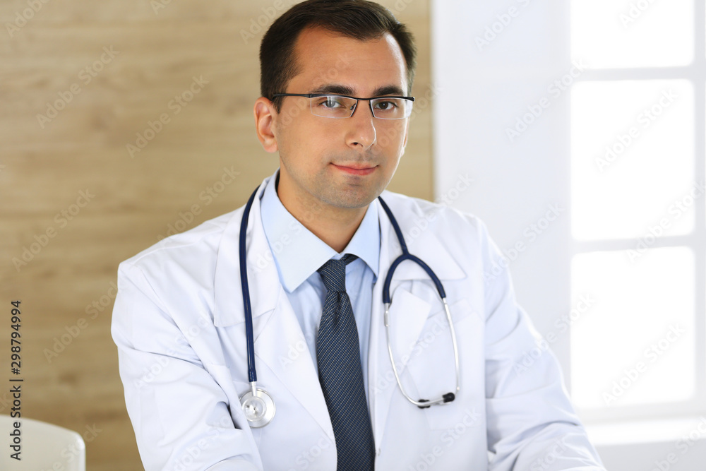 Doctor man typing at laptop computer while sitting at the desk at his working place. Perfect medical service in clinic. Data in medicine and healthcare Doctor man typing at laptop computer while sitting at the desk at his working place. Perfect medical service in clinic. Data in medicine and healthcare
