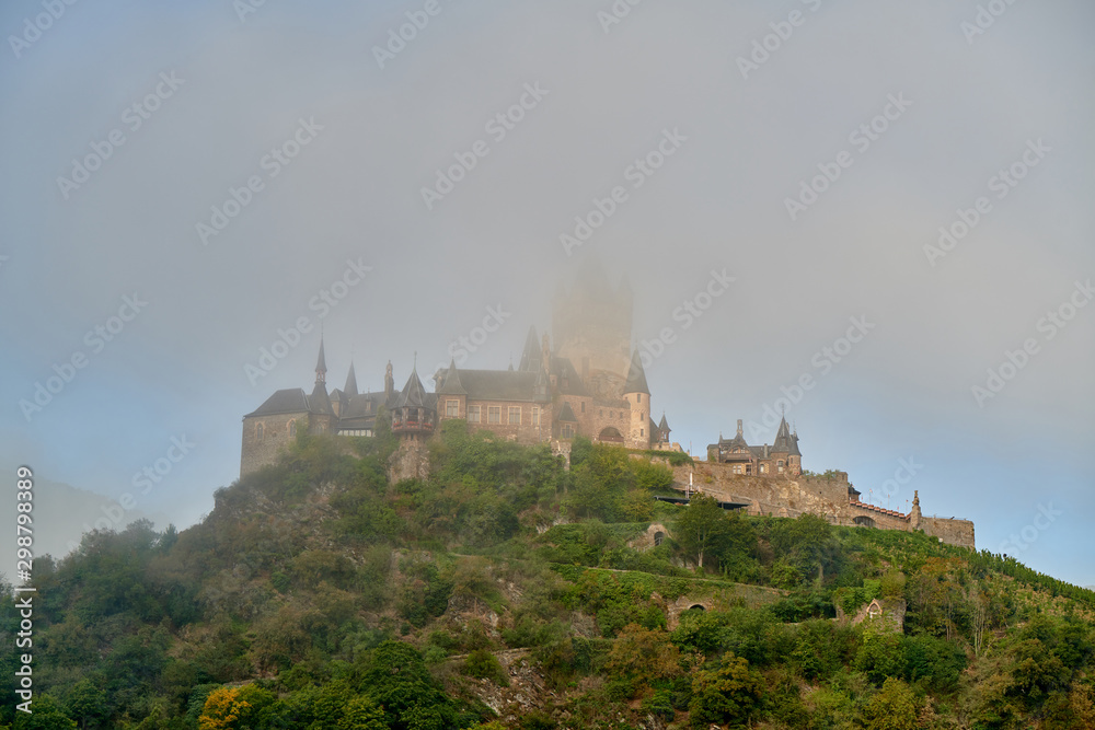 Beautiful Reichsburg castle in morning fog on a hill in Cochem town, Germany