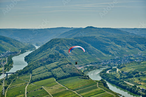 Paraglider over Moselle River bend near Bremm town, Germany. Hills with vineyards, river loop and road along the river. Meander of the Moselle.