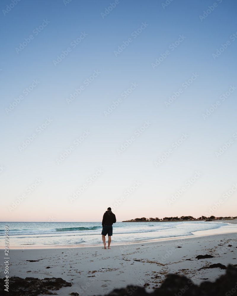 Beautiful drone photography of a man walking on Sorrento beach and ocean at sunrise, Perth Western Australia.
