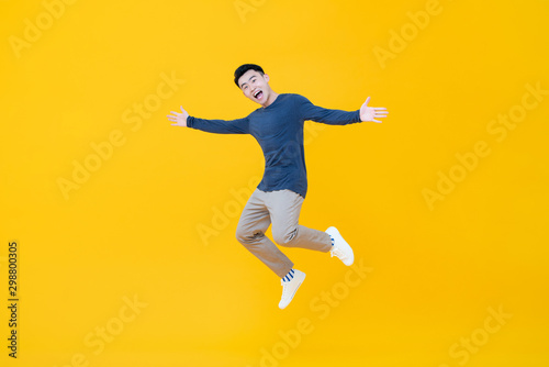 Asian man smiling and jumping with arms outstretched