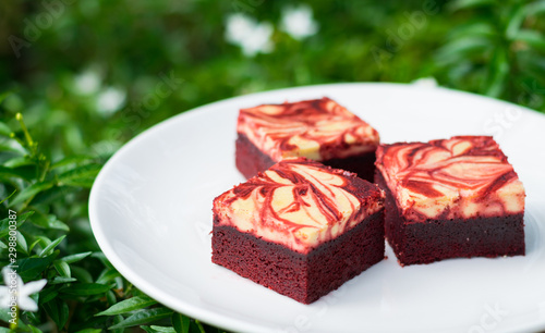 Red velvet cream cheese brownies on white dish
