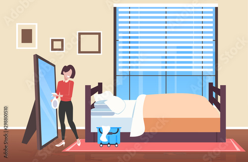 woman cleaner holding rag and spray plastic bottle female janitor spraying and wiping mirror cleaning service concept modern bedroom interior full length sketch horizontal vector illustration