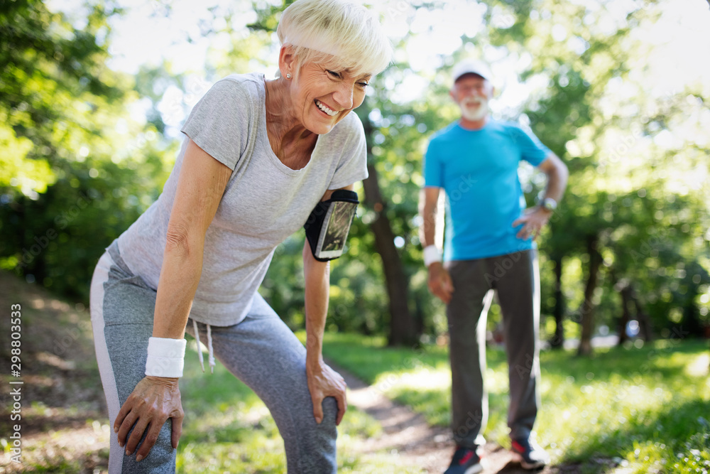 Beautiful senior couple running outside in forest Beautiful senior couple running outside in forest