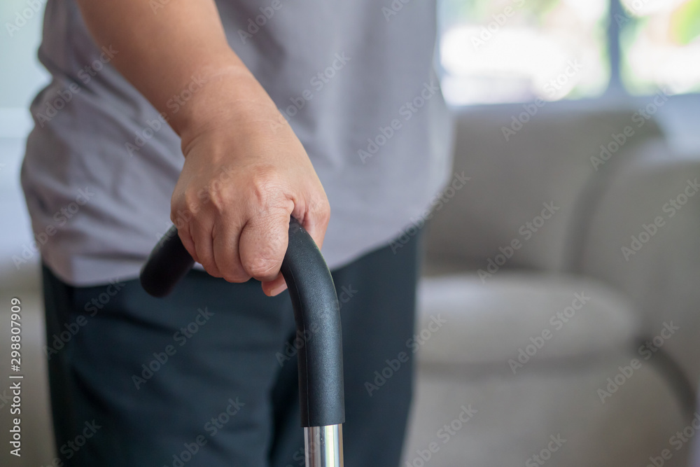 old senior woman with walking disability, hand holding cane as walking aid