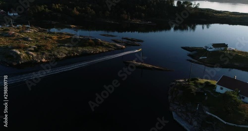 Aerial footage of speed booat crossing peaceful blue water near bautiful island.  photo