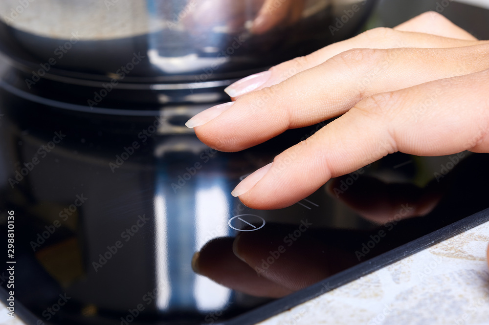 Woman hand includes modern induction stove Woman hand includes modern induction stove