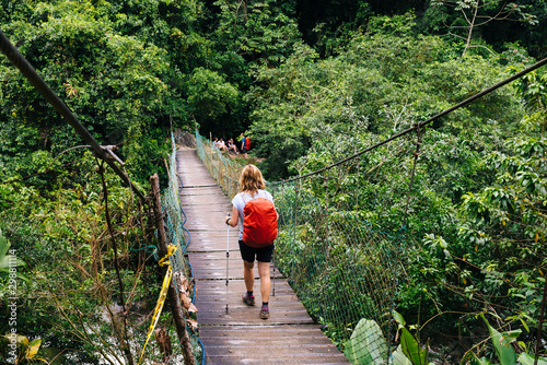 A woman with a daypack and walking sticks is hiking through the dense rainforest of the Sierra Nevada to the pre-Columbian city Ciudad Perdida photo