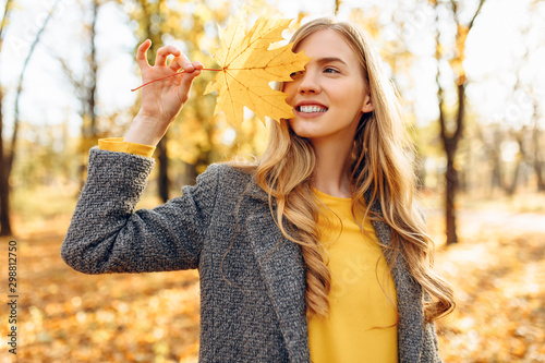 Happy young girl smiling with autumn yellow leaf in Park